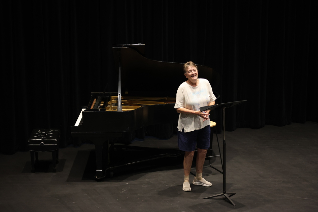 Dr. Alesio rehearses in front of a grand piano on stage.