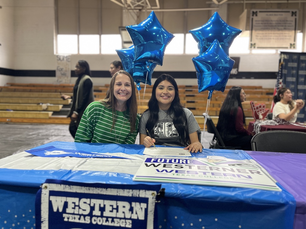 Future Westerner student signs WTC commitment paperwork sitting next to President Sharp at table with blue balloons and Western Texas College materials.
