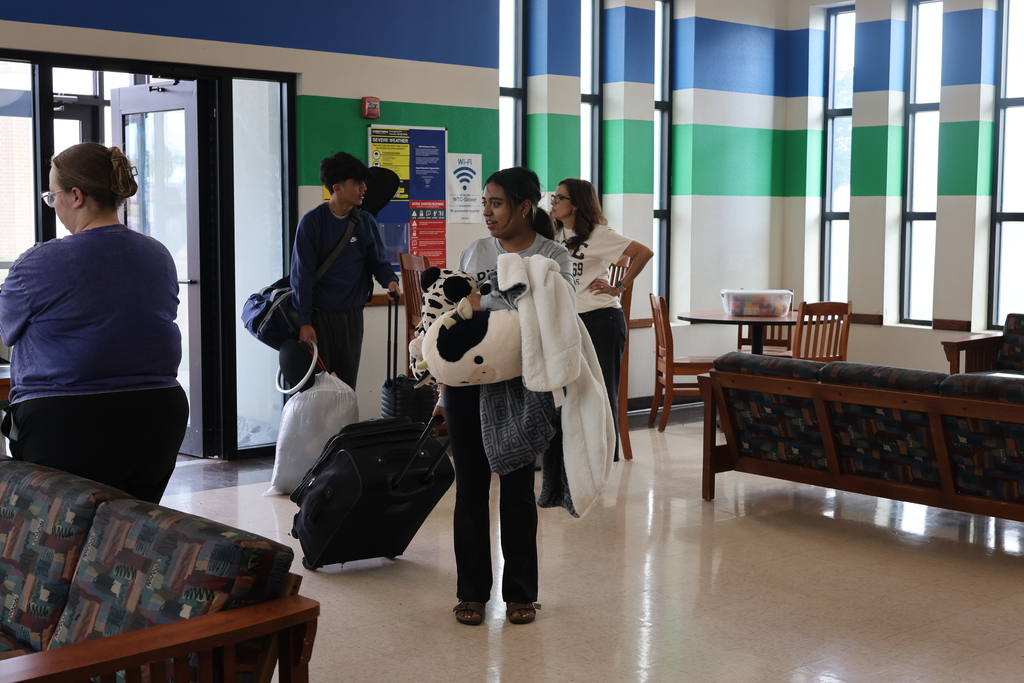 Upward Bound students carry suitcases, pillows, and blankets while checking into campus housing for move-in day.