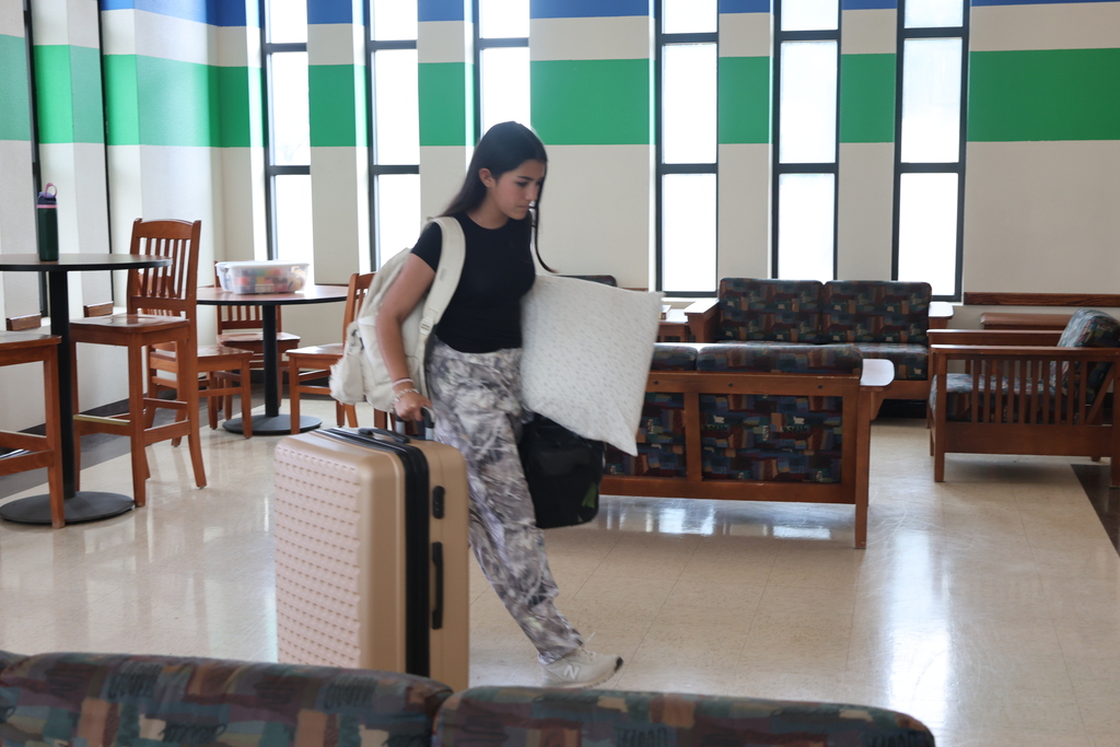 An Upward Bound student rolls a suitcase through the Student Commons on move-in day.