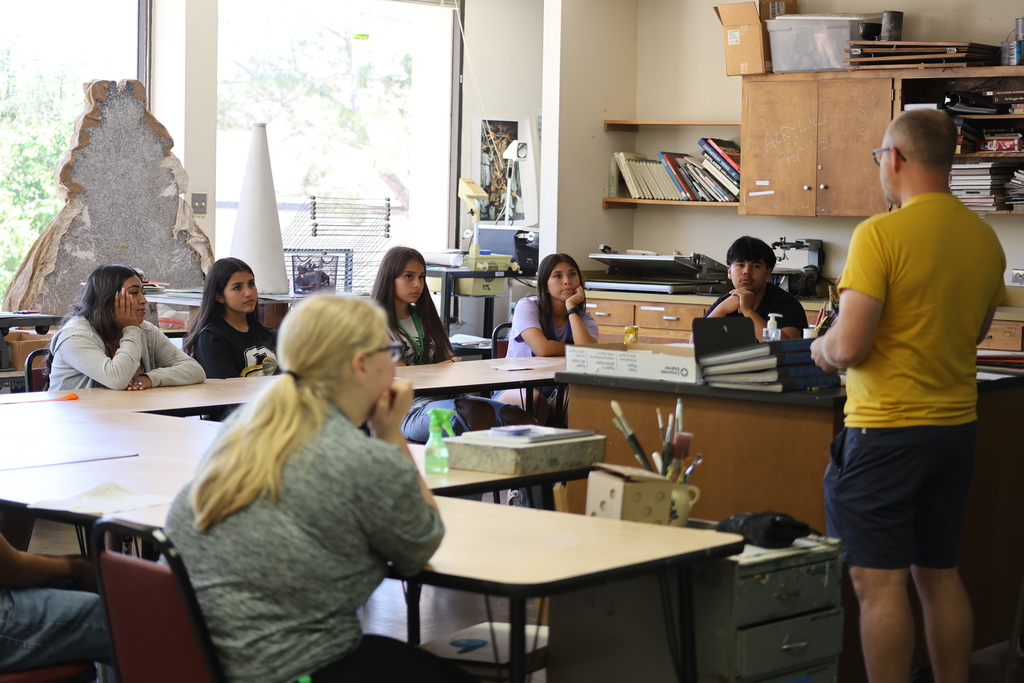 Art instructor leads classroom discussion while students listen attentively during summer academic program.