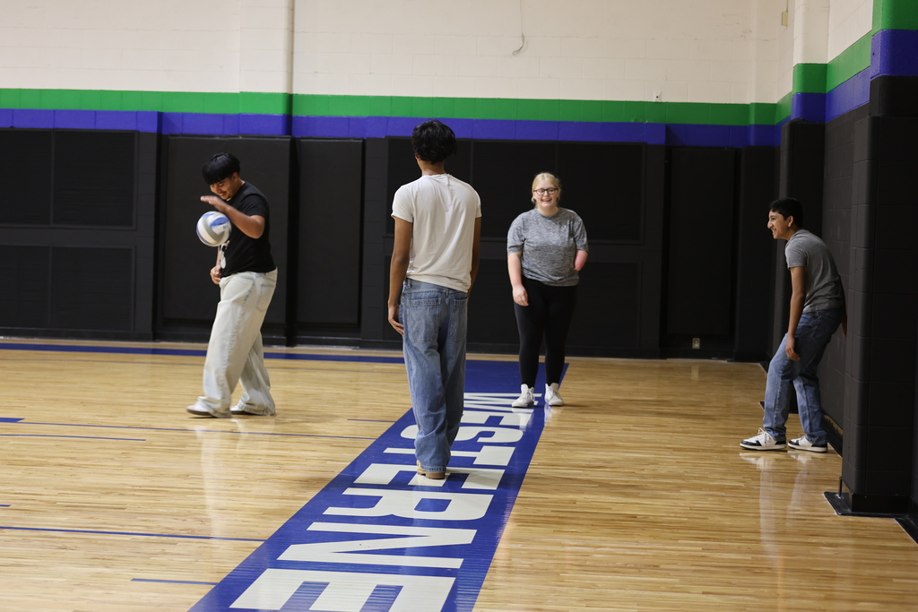 Students laugh and play volleyball together in WTC gymnasium during campus activity.