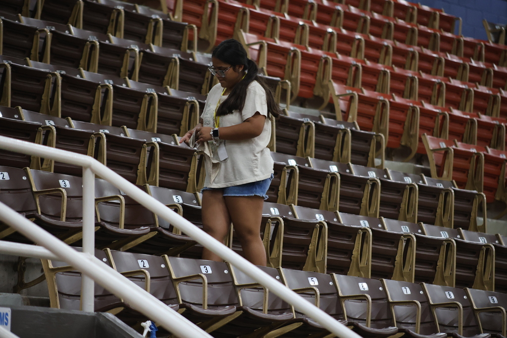 Student wipes down seats in WTC Coliseum during volunteer cleanup activity.