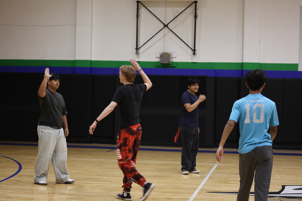 Students celebrate with high-fives while playing an indoor team game in the WTC gym.