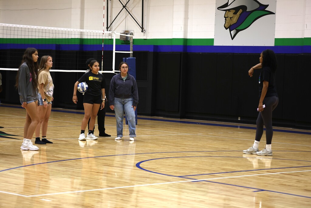 Students listening to volleyball coach explain rules