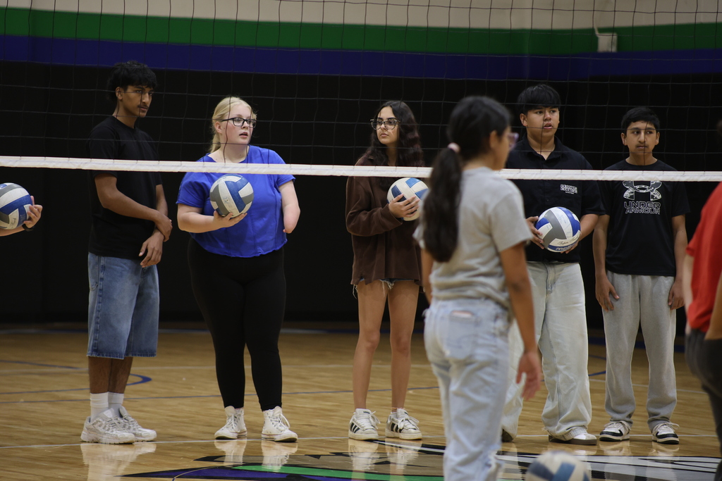 Students listening to volleyball coach explain rules