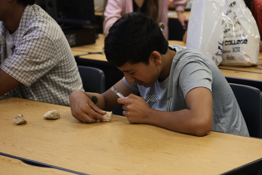 Student studying rocks with a magnify glass.
