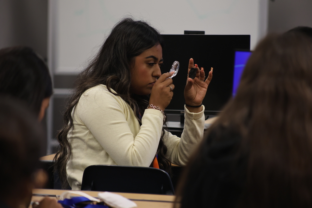 Student studying a rock with a magnify glass.
