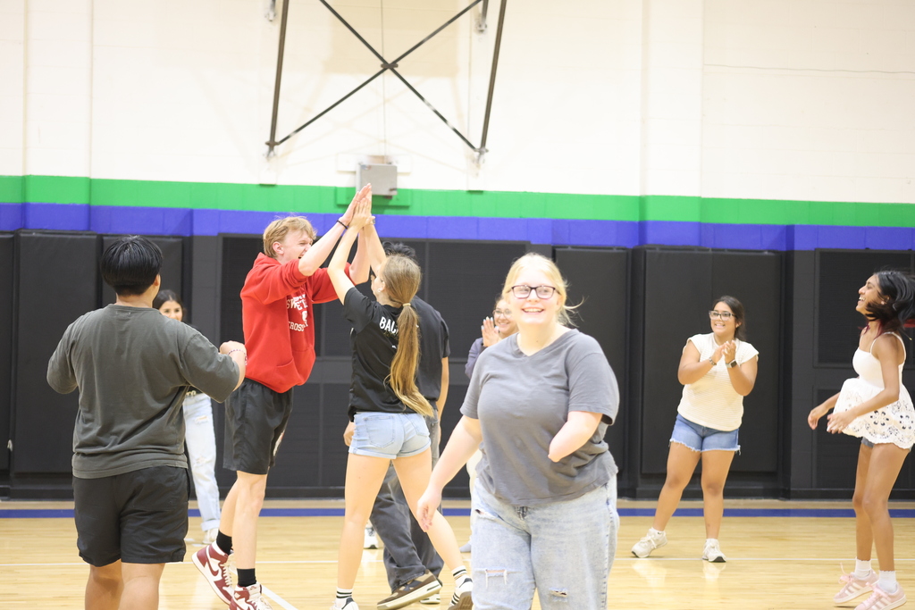 Students celebrate with high-fives during a volleyball activity in the WTC gym.