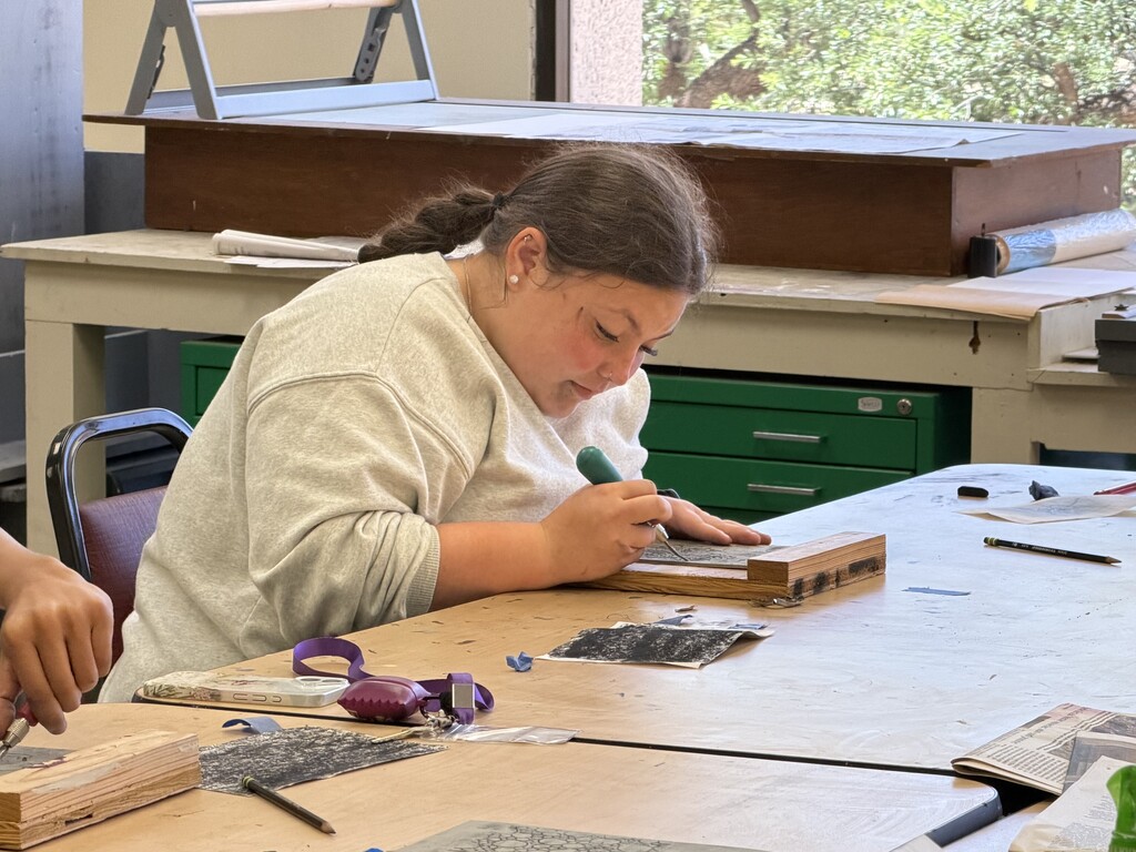 Student carves a printmaking design during an art class at Western Texas College.
