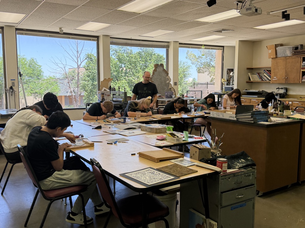 Students create printmaking projects while an instructor assists in the art studio.