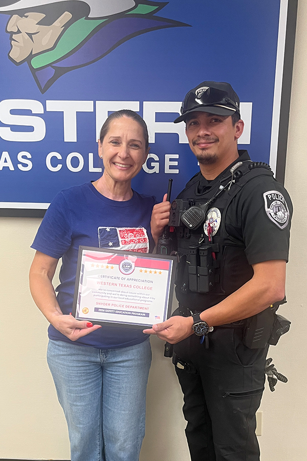 Dr. Sharp and Officer Silva hold a certificate standing in front of  large Western Texas College logo.