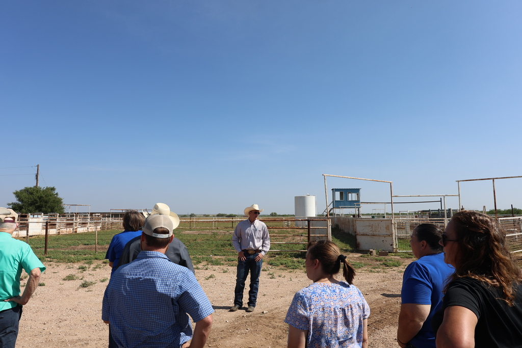 Visitors listen to a presentation outside livestock facilities at the Western Texas College Agricultural & Rodeo Complex.