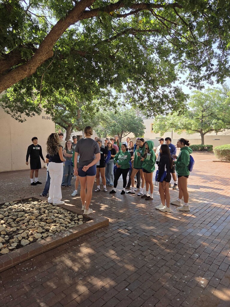 New students gather beneath campus trees during a walking tour at Western Texas College New Student Orientation.