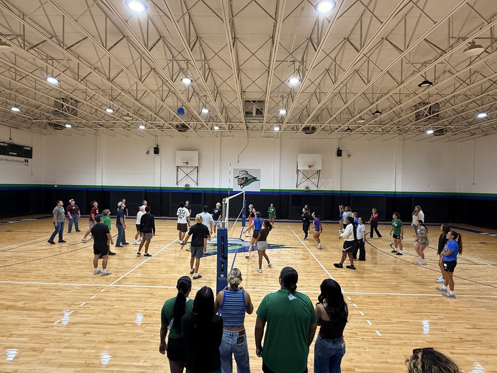 Students gather around a volleyball net during a group activity in the WTC gym.