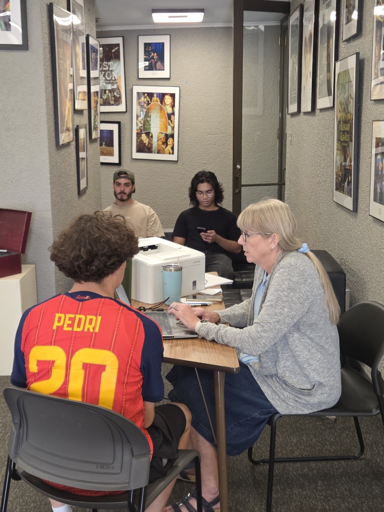 A WTC employee assists a student with Fall Registration while other students wait nearby.
