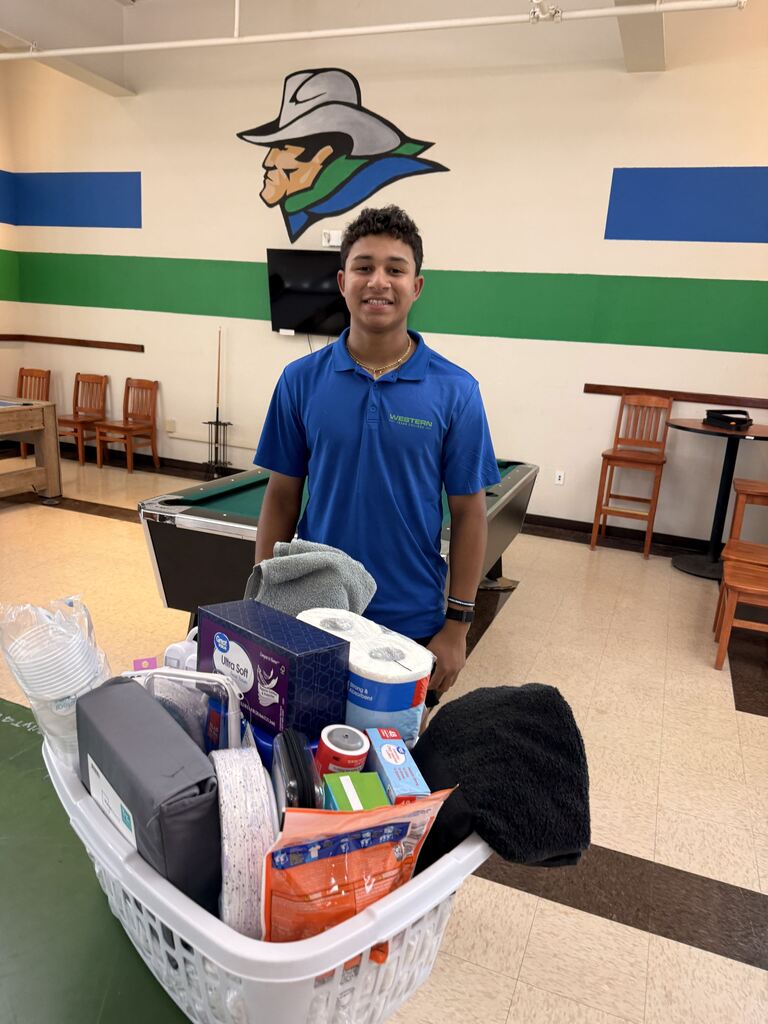 A WTC student stands behind a basket filled with dorm essentials during Westerner Welcome Day.