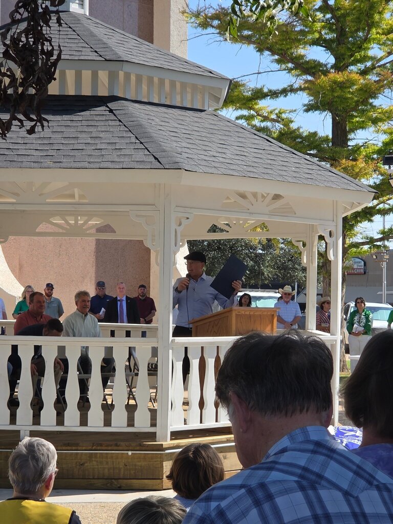 A speaker holds a proclamation while addressing attendees during the Scurry County 150th anniversary celebration.