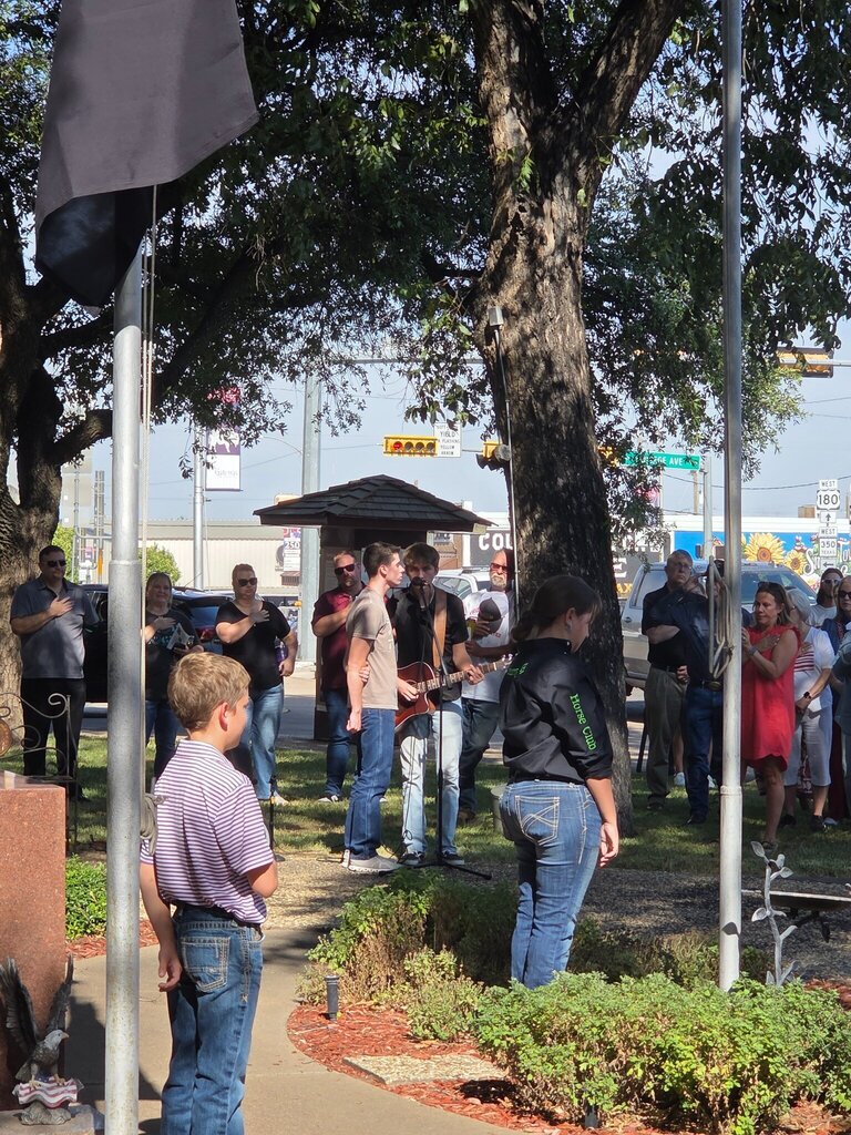 Musicians perform as attendees stand during an outdoor Scurry County 150th anniversary ceremony.