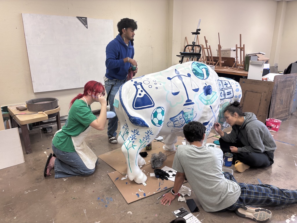 Students encircle the white buffalo while painting it.