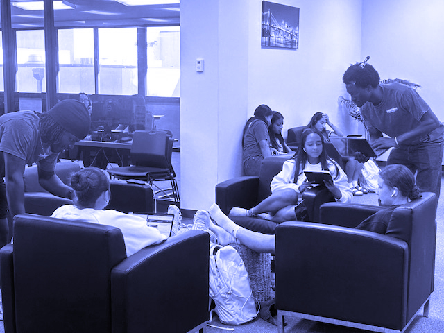 Tutors help students sitting in chairs in the library.