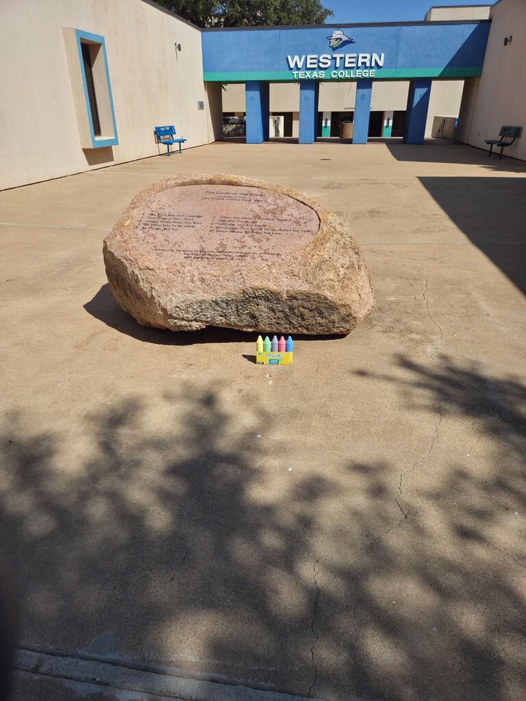 Sidewalk chalk and colorful chalk pieces sit near the Code of the West monument on the WTC campus.