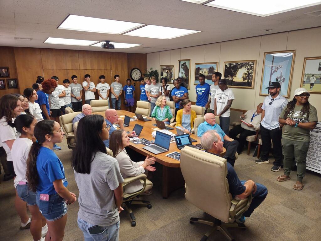 WTC cross country and track student-athletes stand before the Board of Trustees during a campus meeting.