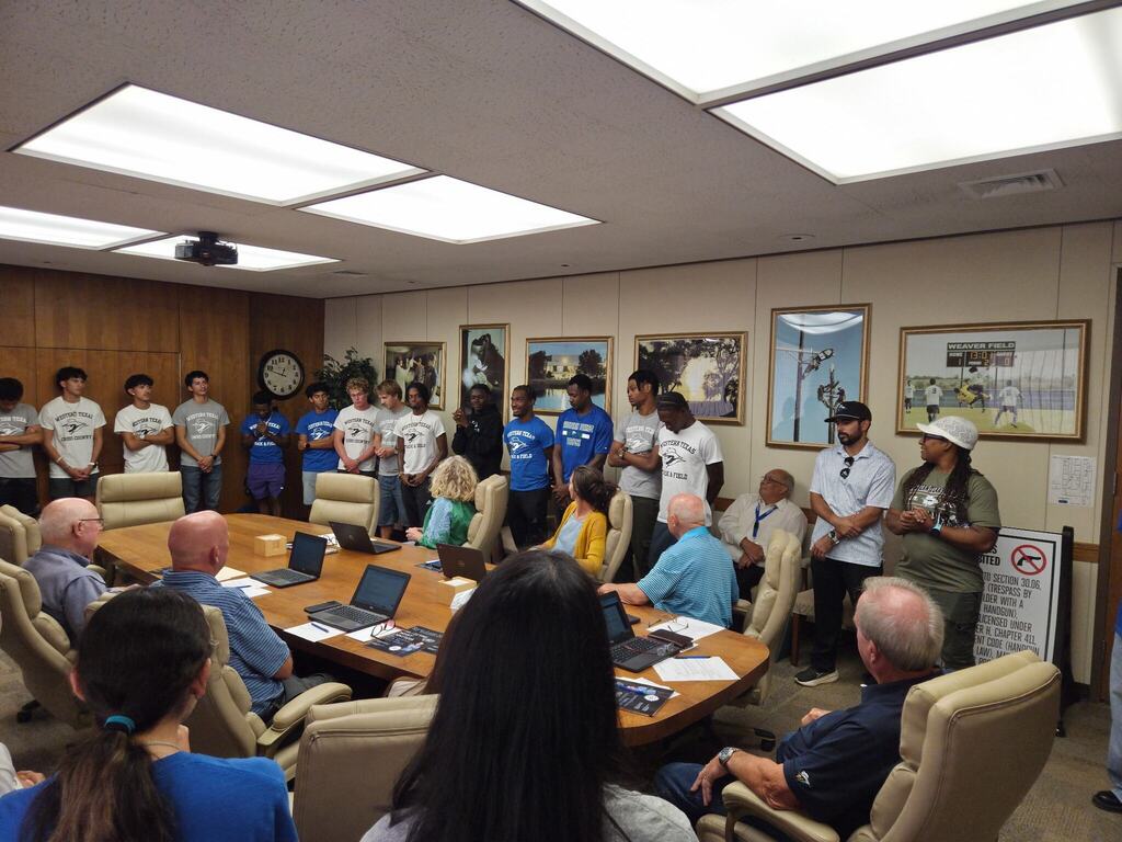 WTC cross country and track and field student-athletes stand before the Board of Trustees during a campus meeting.