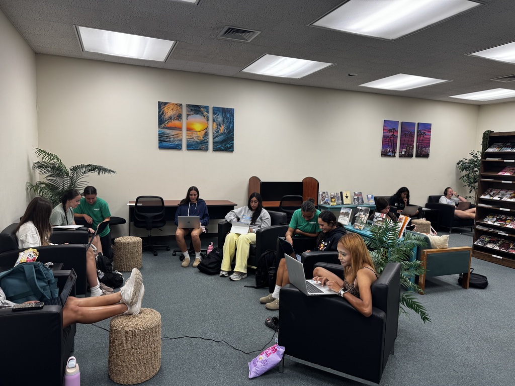 A Texas Tech University representative sits at an information table on the Western Texas College campus.  Students study and work together on laptops in a comfortable seating area inside the Western Texas College library.