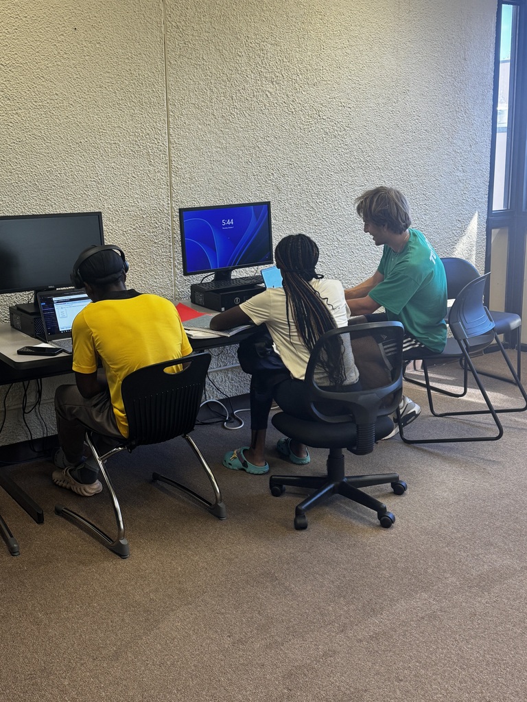 A tutor helps students sitting in front of computers in the computer lab.