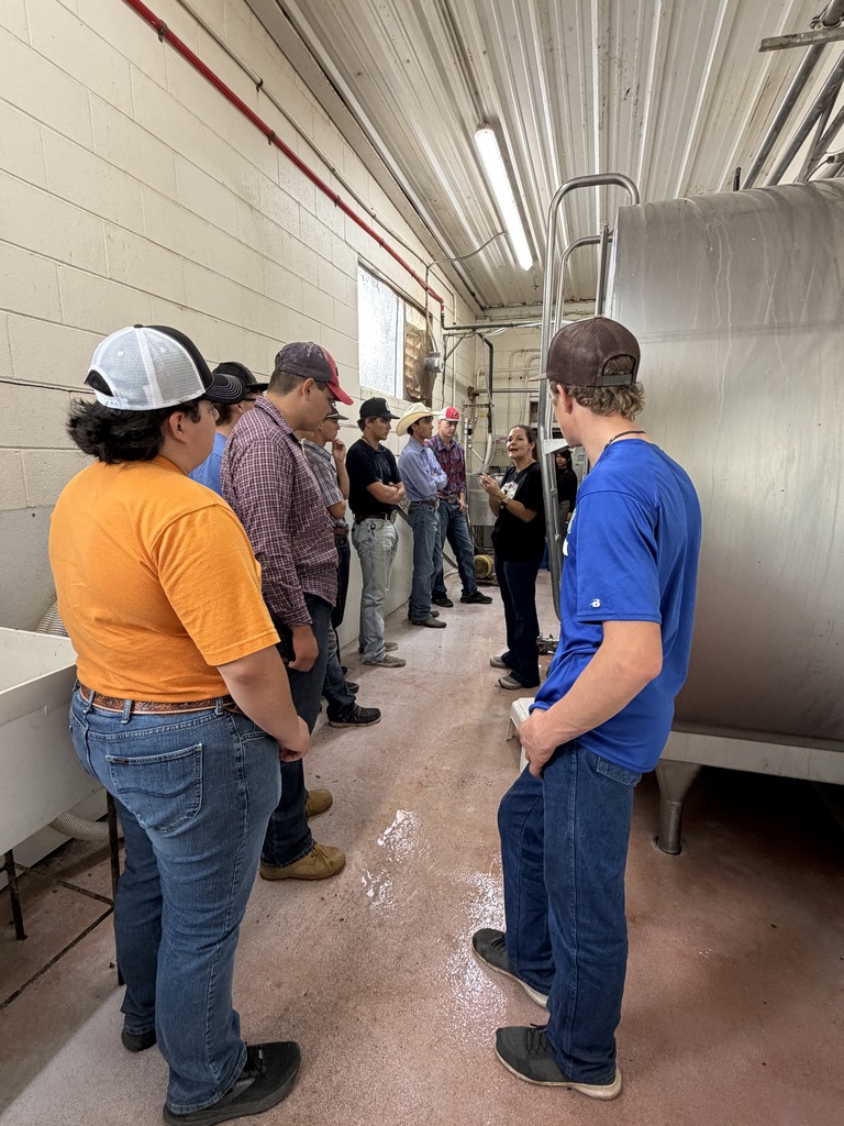 Western Texas College students learn about dairy operations beside a large stainless steel tank.