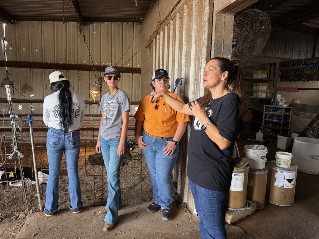 A dairy farm representative explains farm operations to Western Texas College students inside a livestock barn.