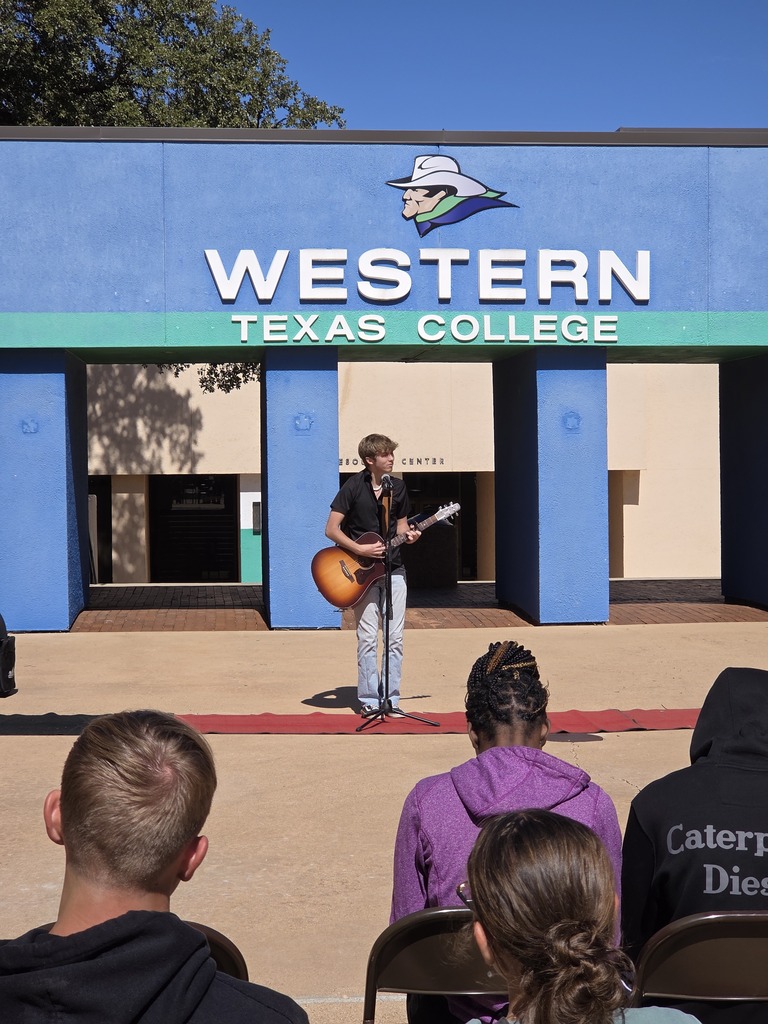 Keegan Bufkin sings and plays the guitar in front of the arch.