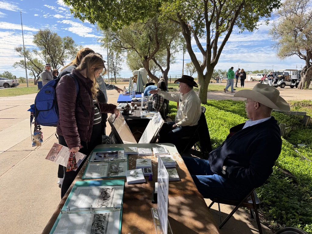 A woman stands at a table looking at the art.