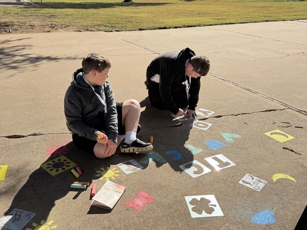 Two boys create art with chalk.
