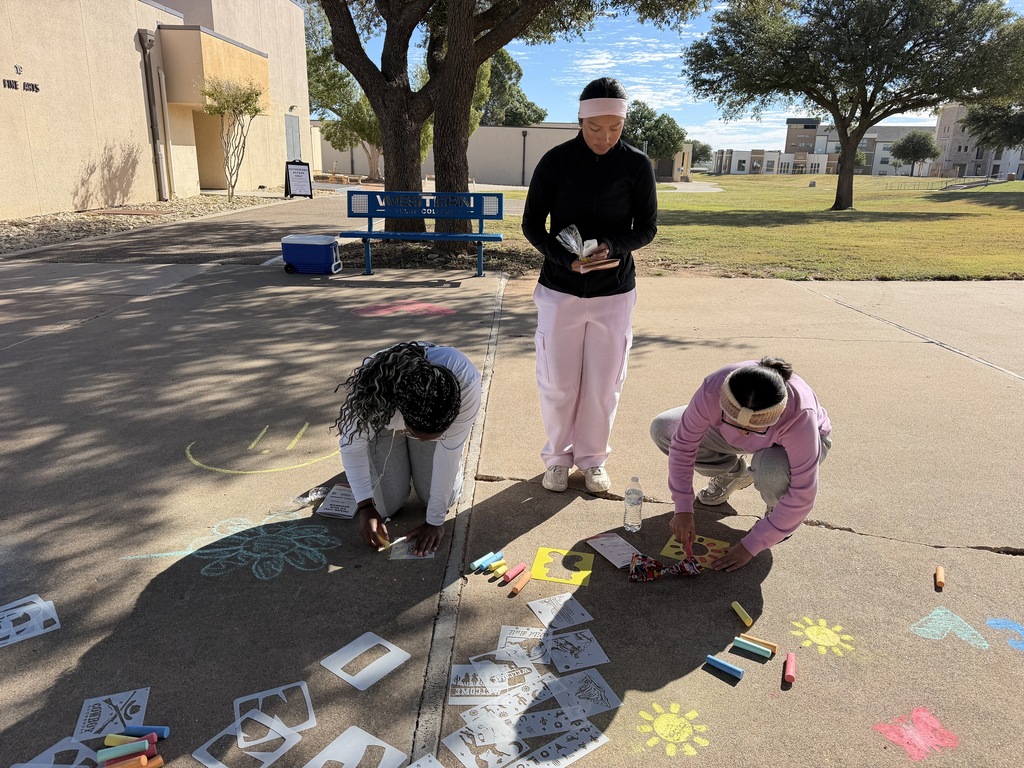 Two studnets use chalk stencils whil another student watches.