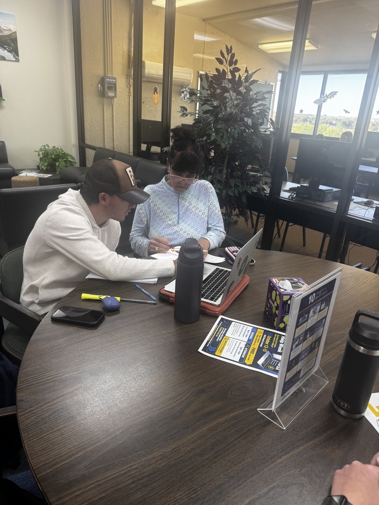 A Western Texas College student and tutor review an assignment together at a table with a laptop and study materials.