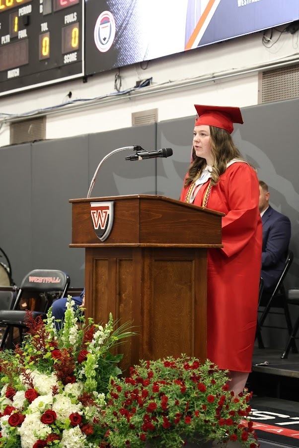 Sierra Chalk talking at podium in cap and gown
