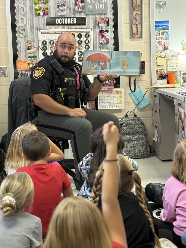 Deputy Freeman reading a book to a group of students