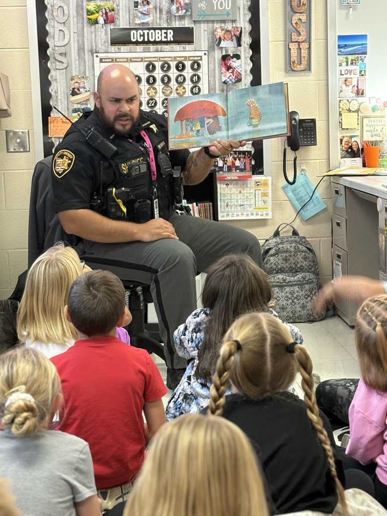 Deputy Freeman reading a book to a group of students
