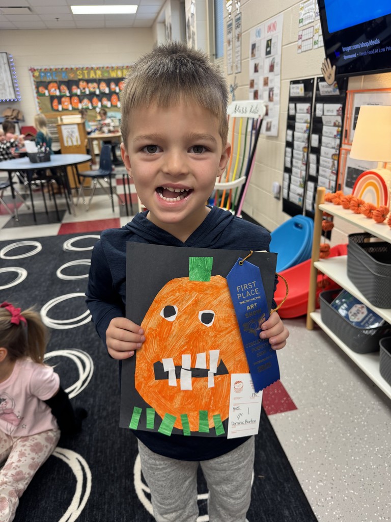 Preschool Student holding prize winning pumpkin artwork 