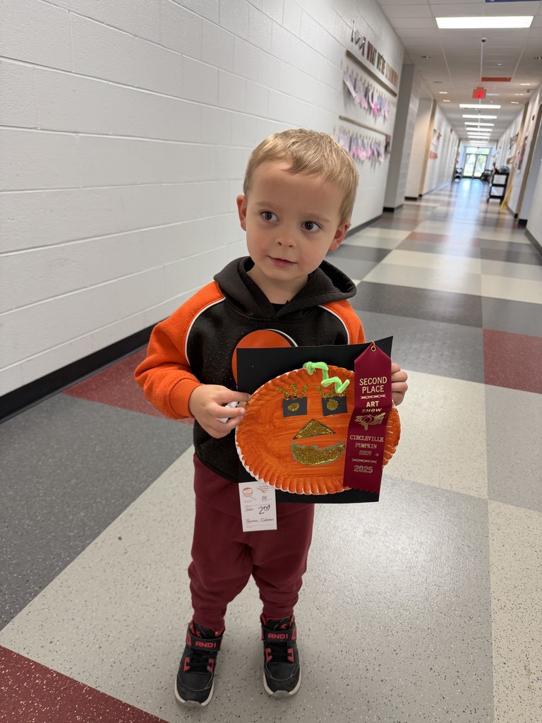 Preschool Student holding prize winning pumpkin artwork 
