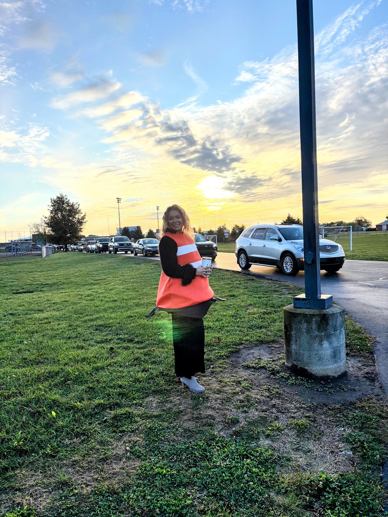 Mikaela dressed up as an orange traffic cone posing in front of cars