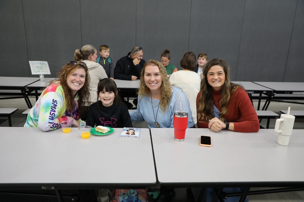 Students with teacher and family in cafeteria