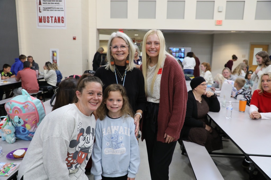 Students with teacher and family in cafeteria