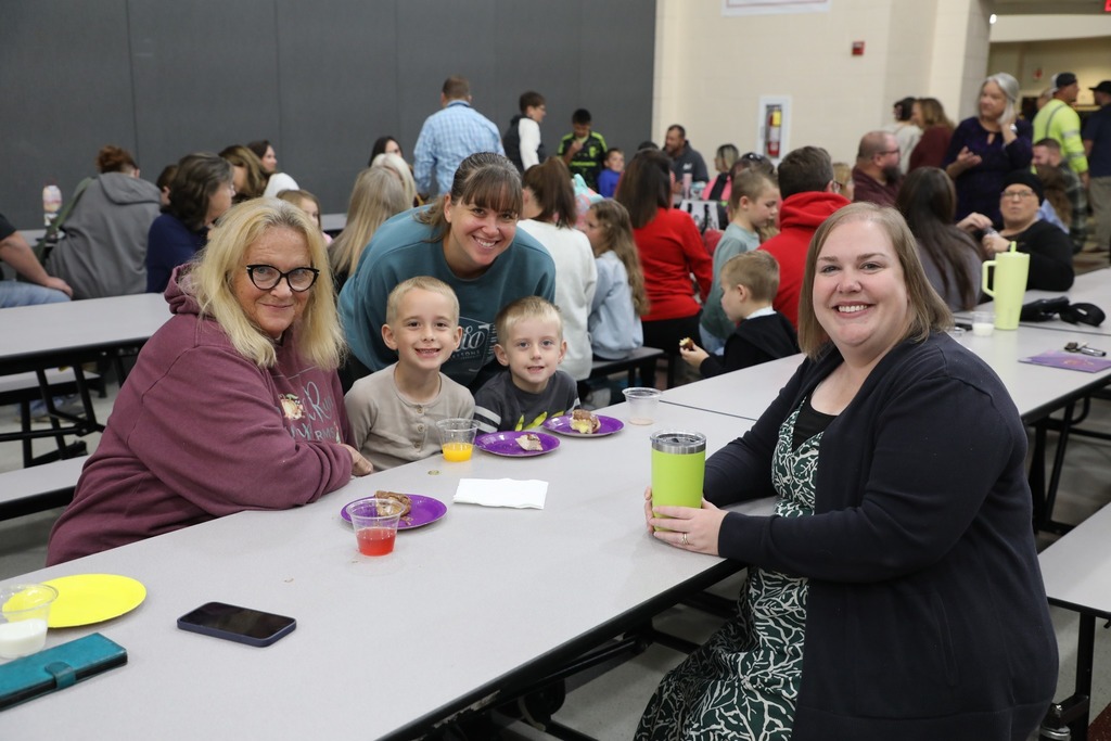 Students with teacher and family in cafeteria