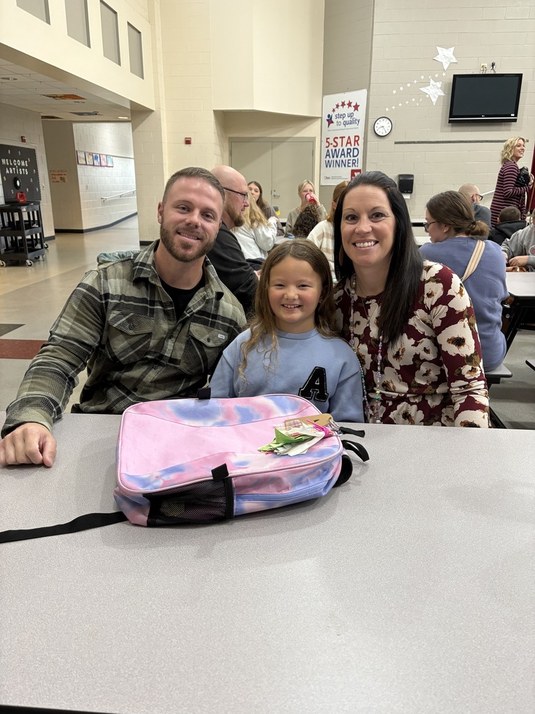 Students with teacher and family in cafeteria