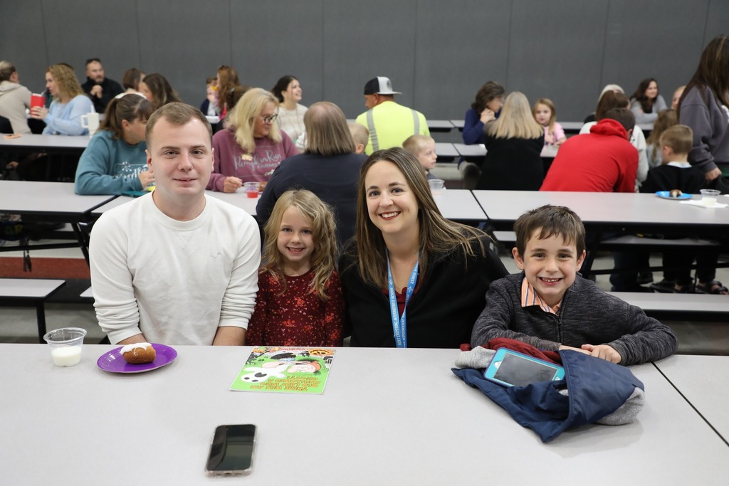 Students with teacher and family in cafeteria
