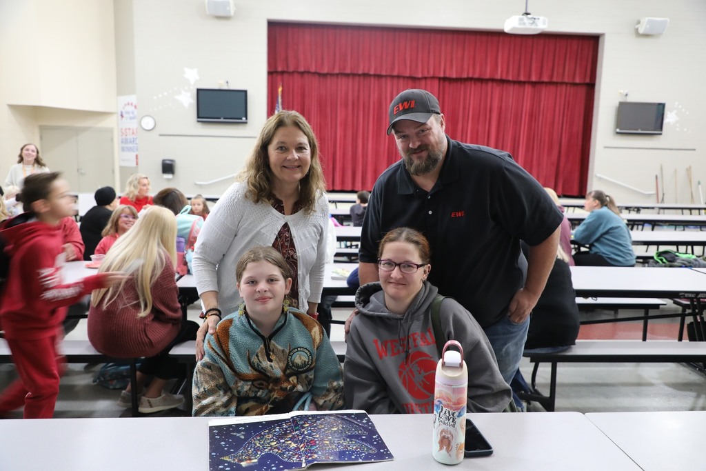 Students with teacher and family in cafeteria