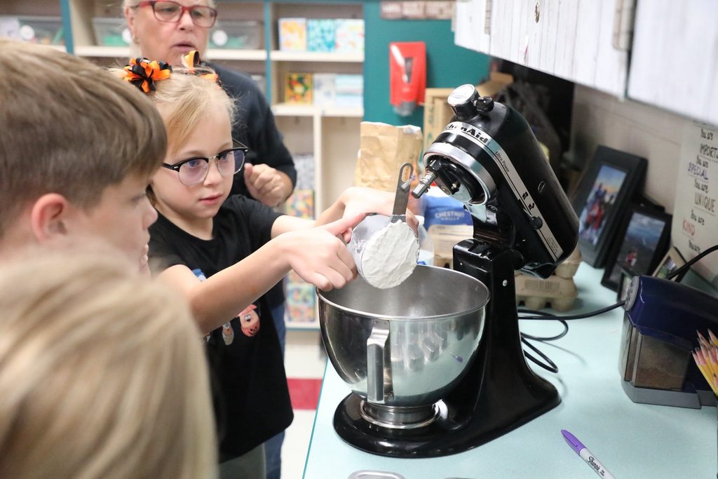 Student pouring flour into a mixing bowl